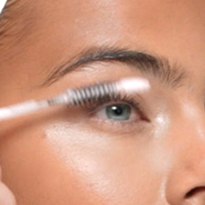 SWATI Cosmetics model applying tourmaline lash + brow booster serum on lashes.